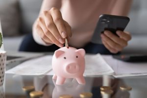 woman putting coin piggybank